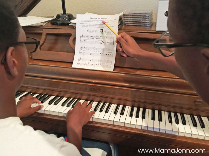 a boy teaching piano lessons to another boy